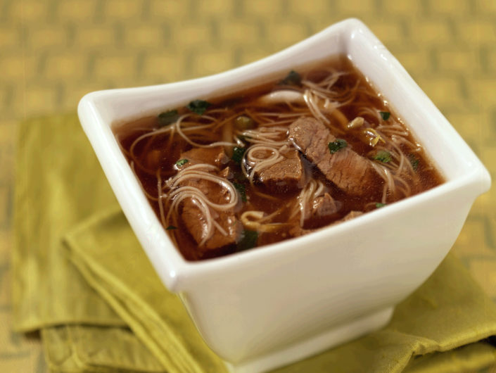 thinly sliced grilling steak cooks in bowl when hot broth is poured over.